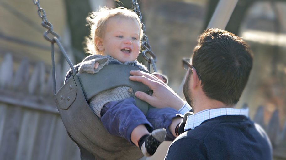 dad pushing baby on swing